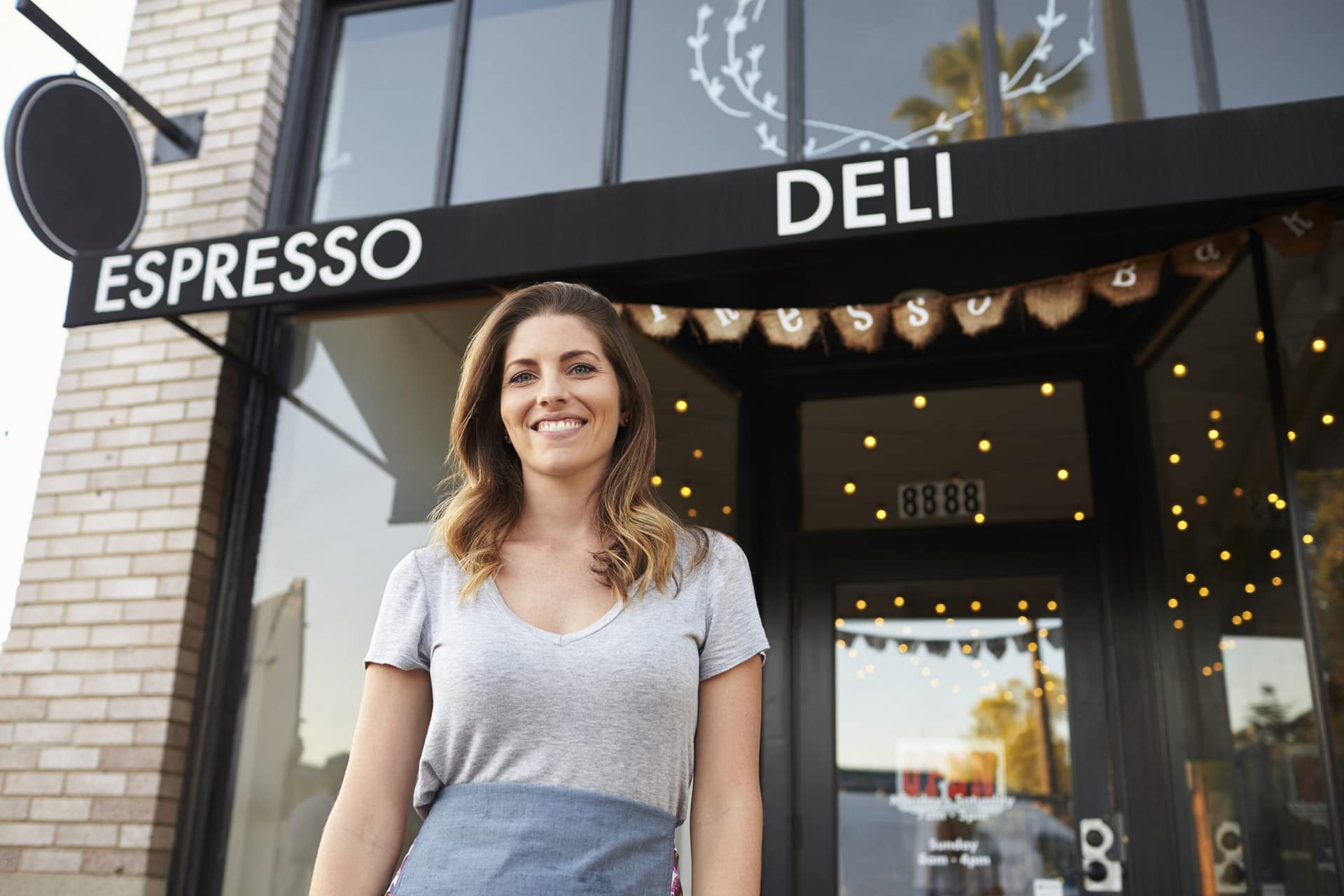 Young white female business owner standing outside cafe Avance de Efectivo
