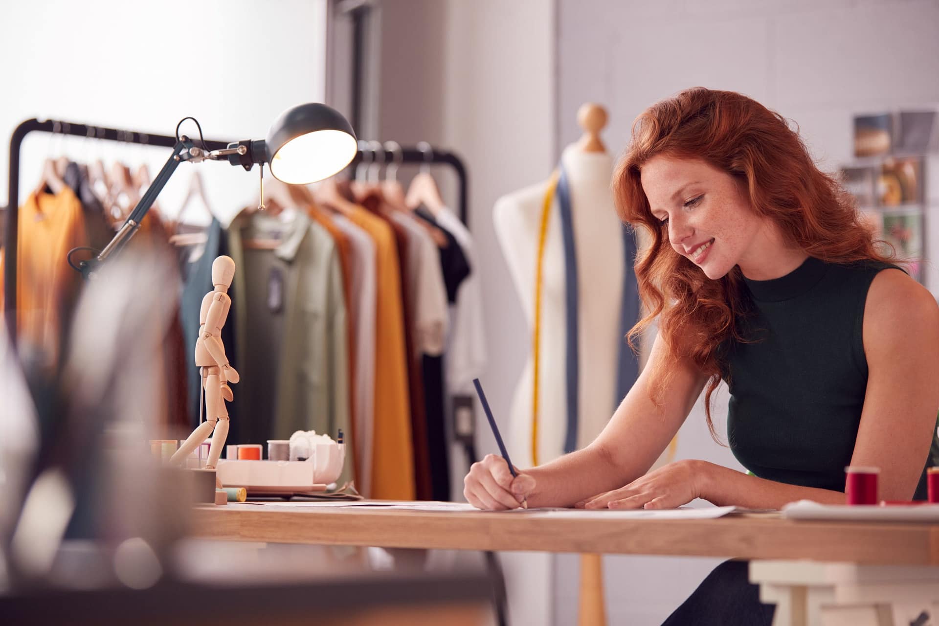 Female Student Or Business Owner Working In Fashion Sketching Designs In Studio Avance de Efectivo
